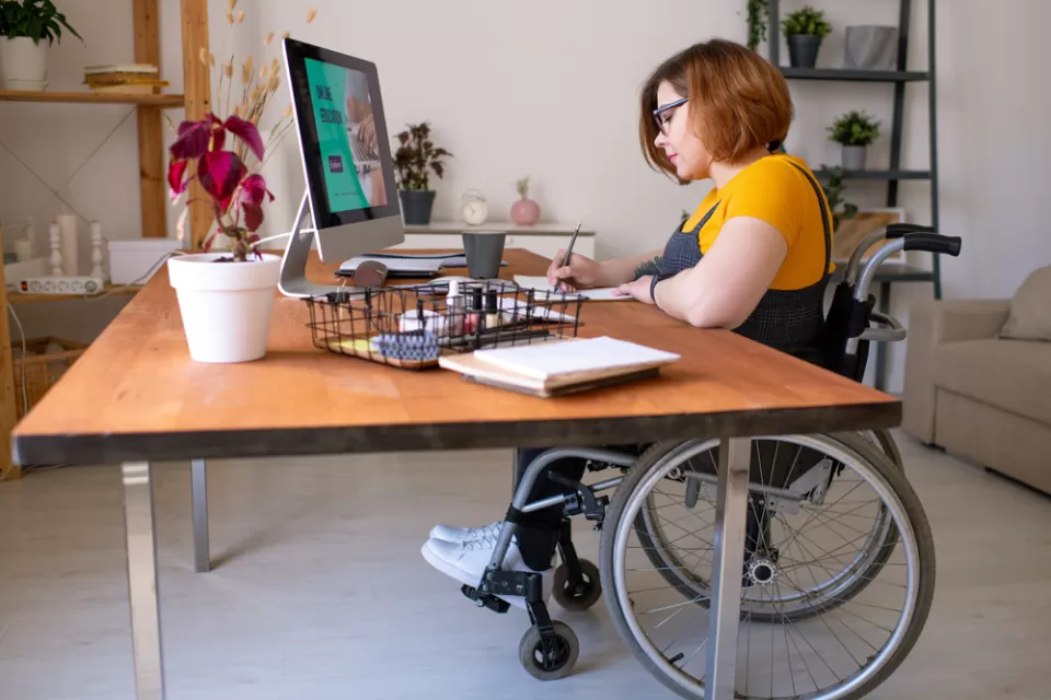 Woman in wheelchair working at a home office desk